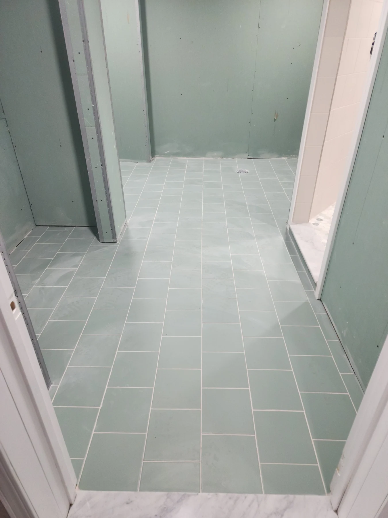 April 2023 construction progress: floor tile installed, with walls still at the finishing stage.