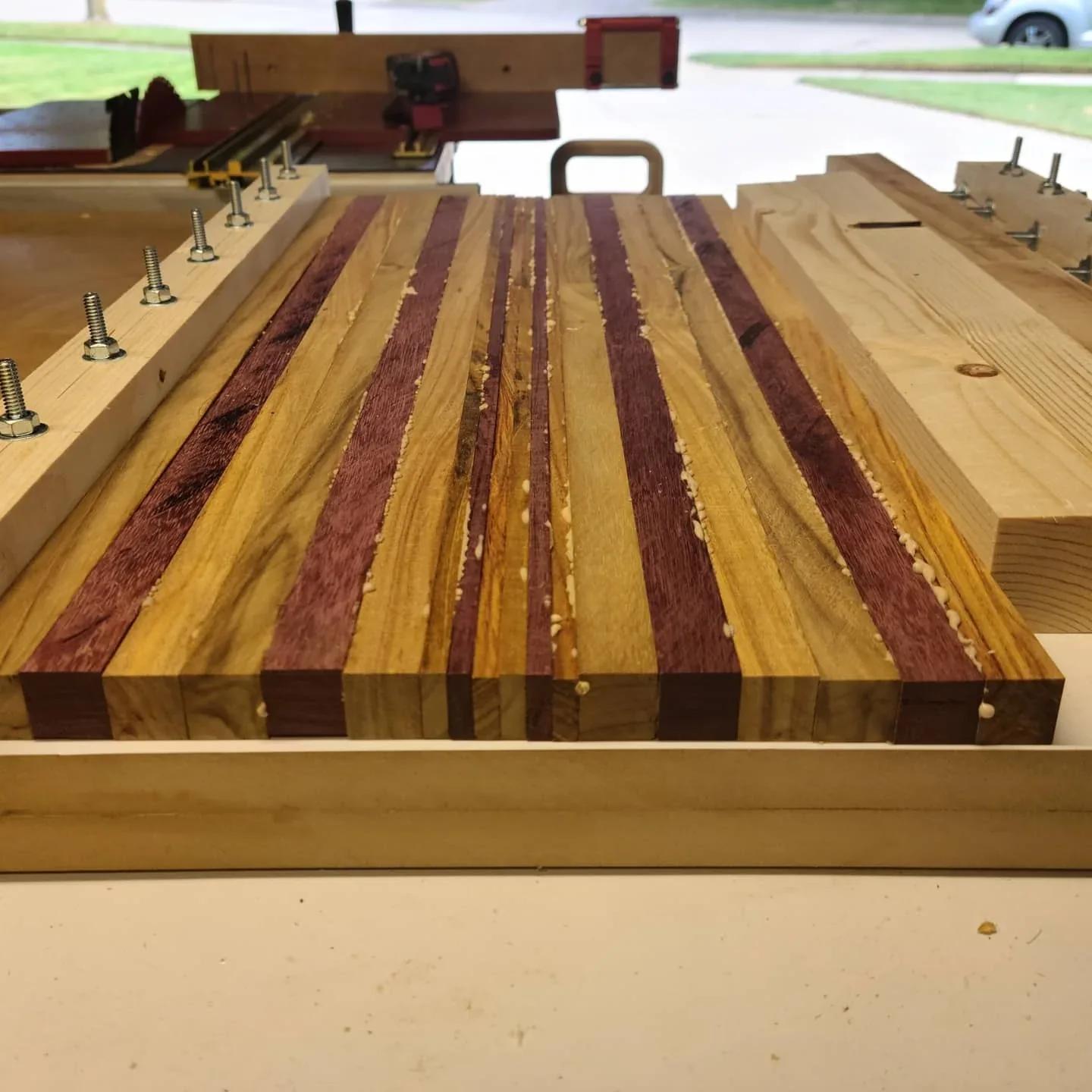 A striped cutting-board glue-up held in a custom clamping frame.