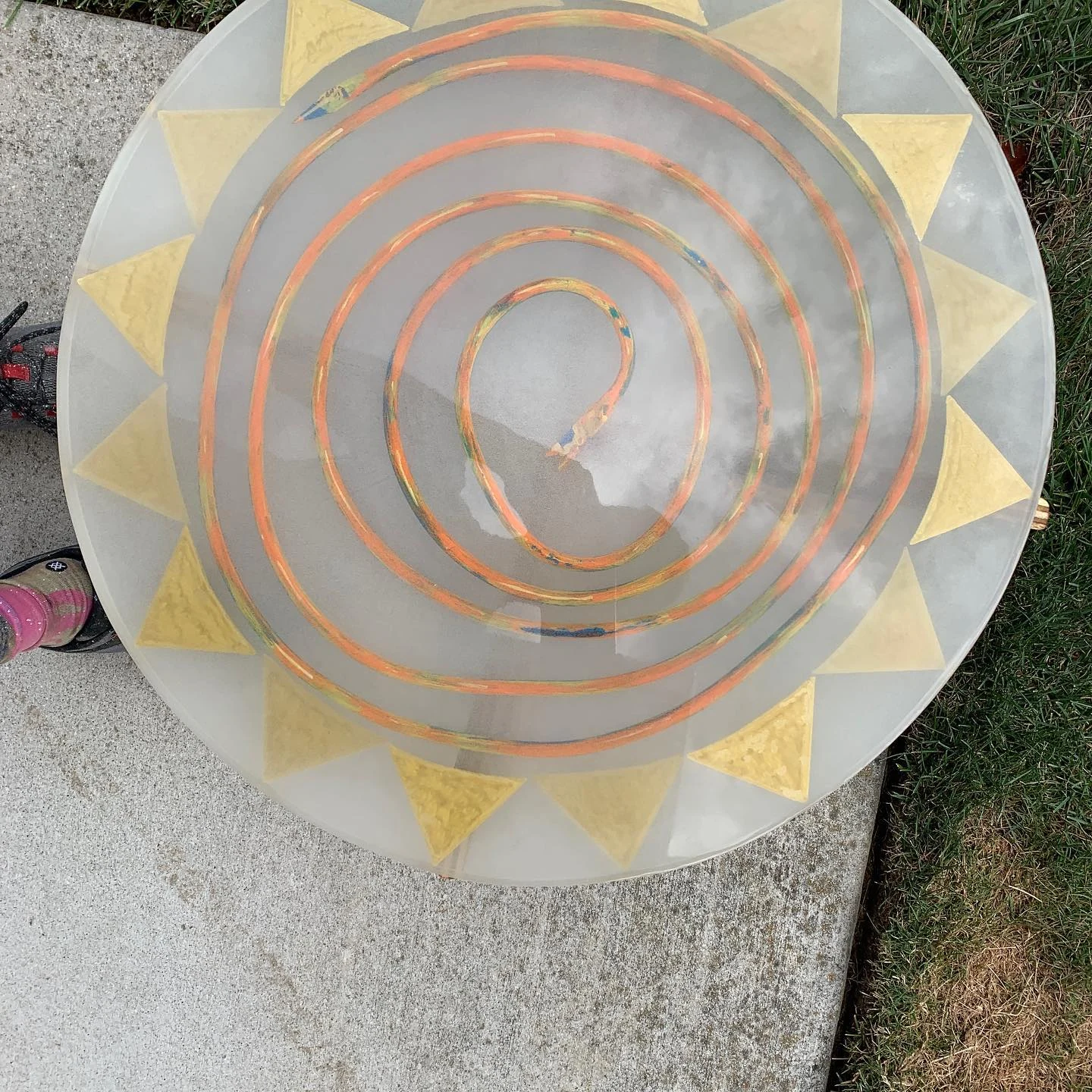 Copper spiral and gold triangular details embedded in a circular resin piece.