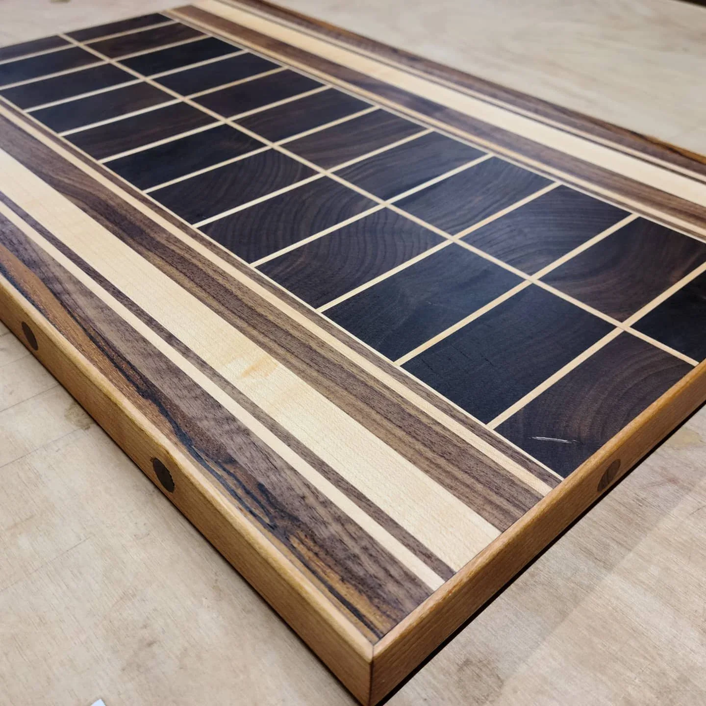 Walnut center, contrasting wood borders, cherry frame, and walnut plugs on the commissioned board.