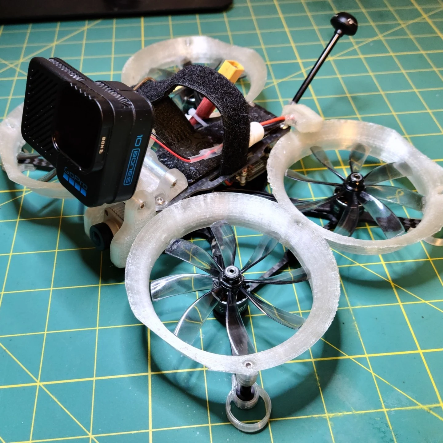 Shendrones Squirt cinewhoop with propeller ducts and a GoPro camera on the cutting mat.