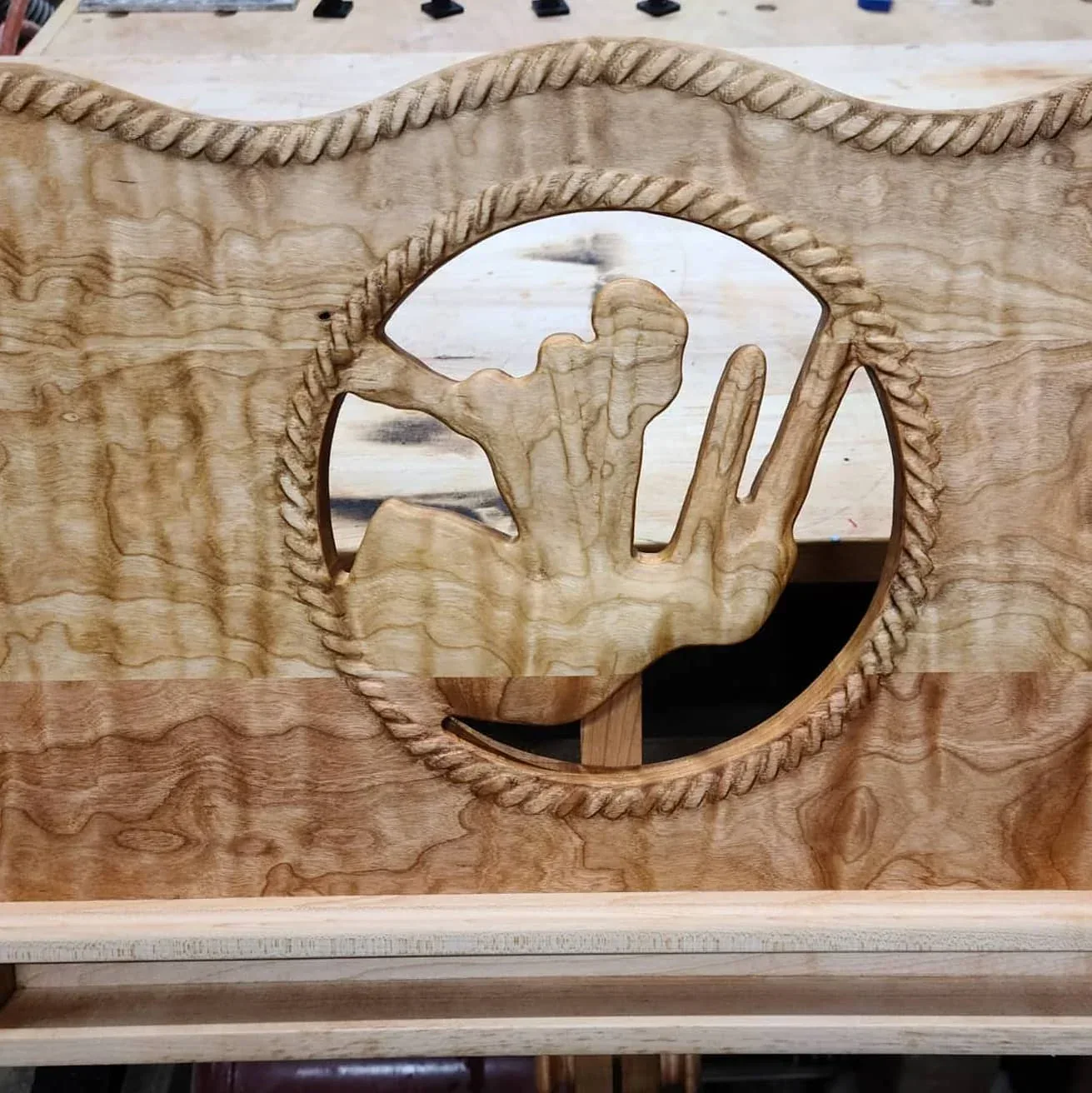 Close-up of the bagpipe motif, carved rope border and figured cherry.