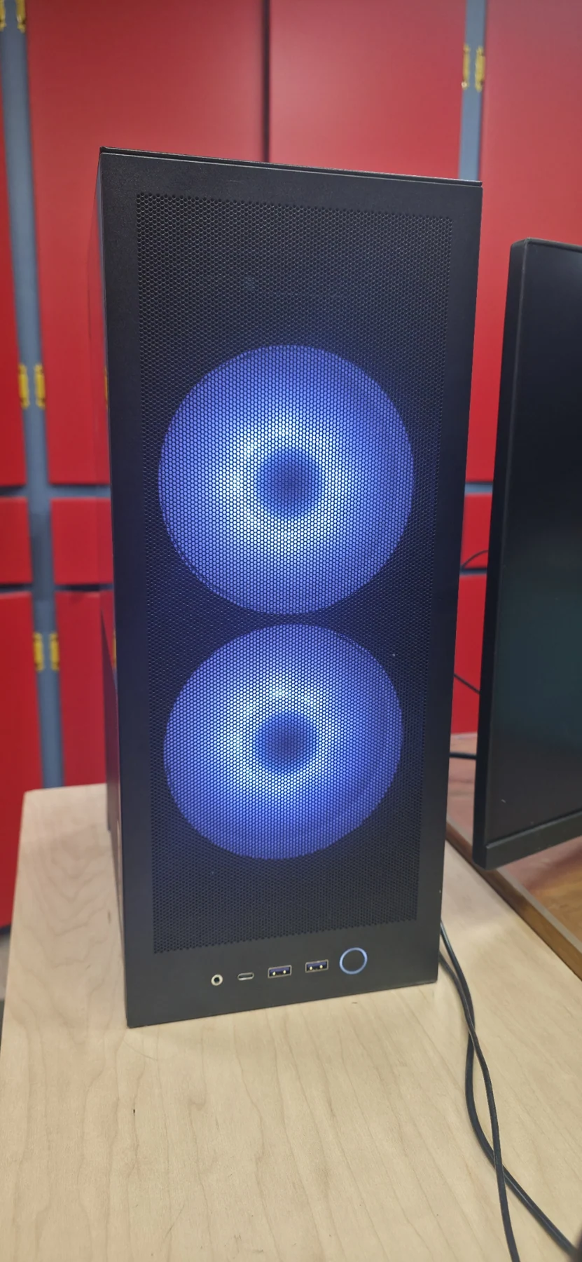 Front view of the recent PC build, with two illuminated fans behind the mesh.