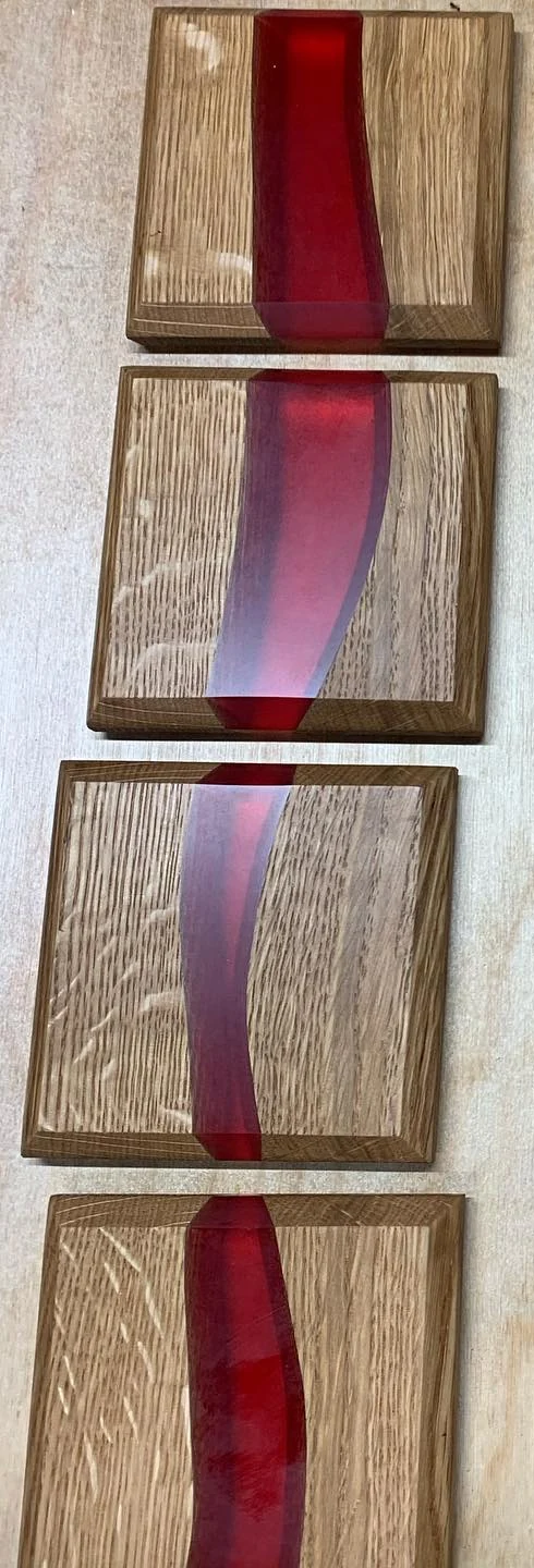 Rectangular quarter-sawn oak coasters with a red resin river. Crop of the original grouped photograph.