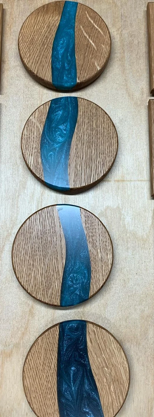 Circular quarter-sawn oak coasters with a blue resin river. Crop of the original grouped photograph.