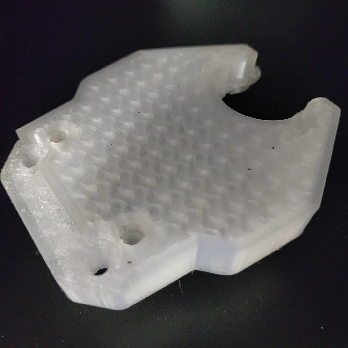 Close view of the translucent TPU replacement showing its mounting holes and printed internal pattern.