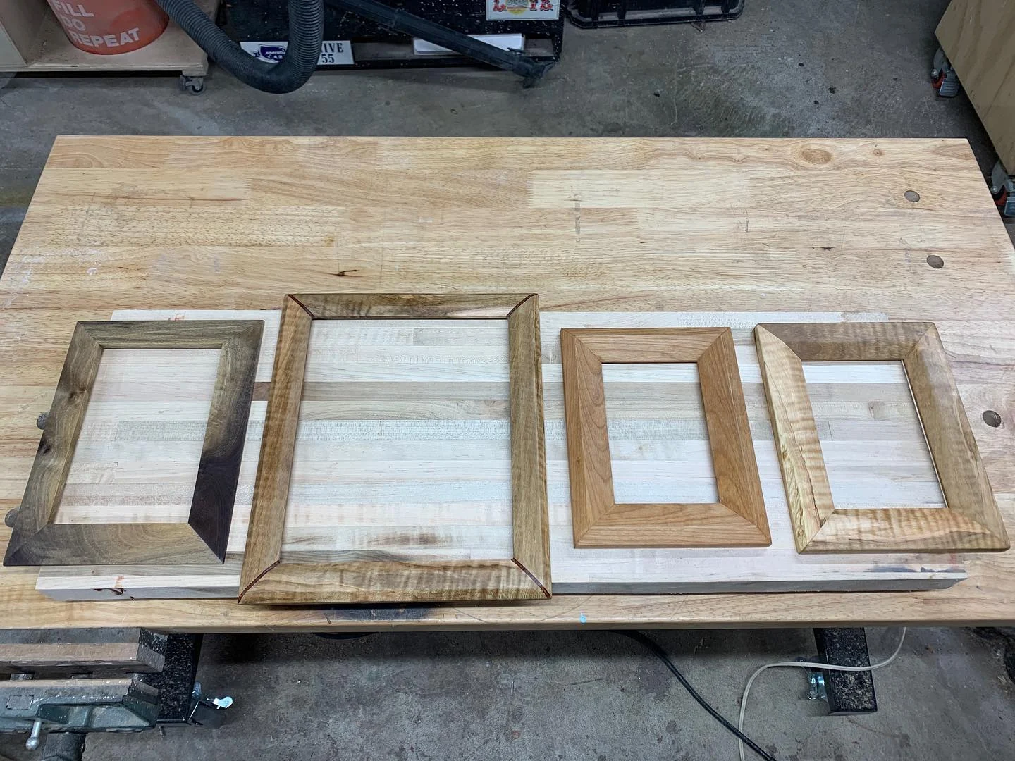 Four wooden picture frames laid out on the workbench.